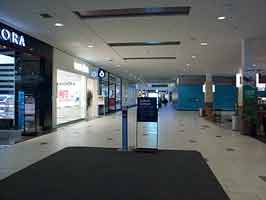 The center entrance hall of the Empire Mall. To the left are various storefronts, to the right is a coffe stand and a work wall.
